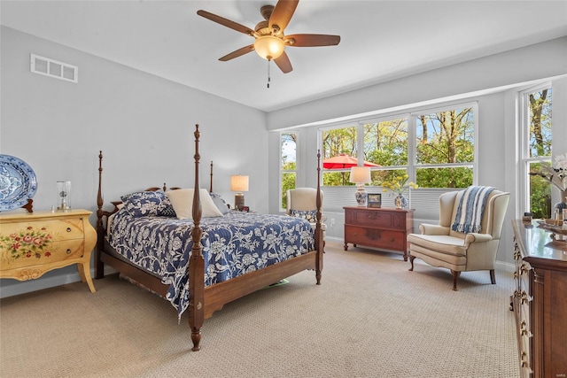 bedroom featuring light colored carpet, visible vents, a ceiling fan, and multiple windows