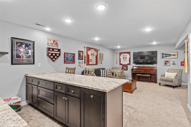 kitchen with recessed lighting, visible vents, light stone counters, and a peninsula