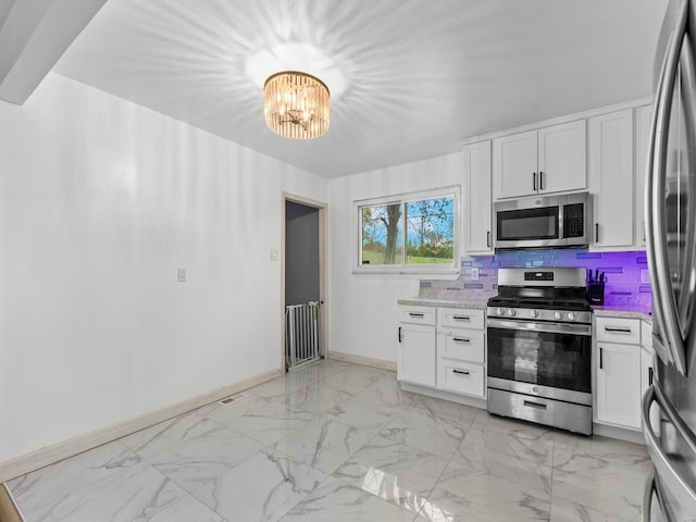 kitchen featuring white cabinets, baseboards, an inviting chandelier, light countertops, and appliances with stainless steel finishes