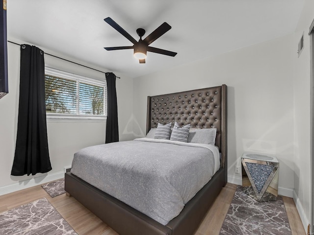 bedroom with wood finished floors, visible vents, a ceiling fan, and baseboards