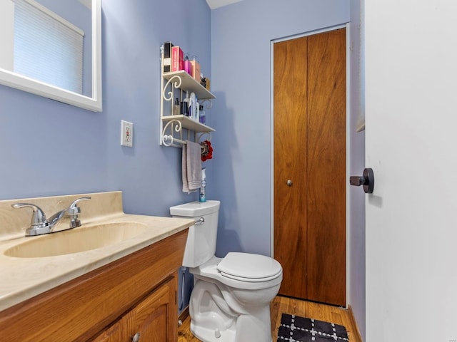 bathroom featuring toilet, vanity, and wood finished floors