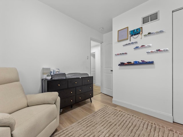 living area with baseboards, wood finished floors, and visible vents