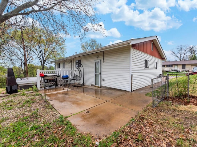 rear view of property with a gate, a patio area, board and batten siding, and fence