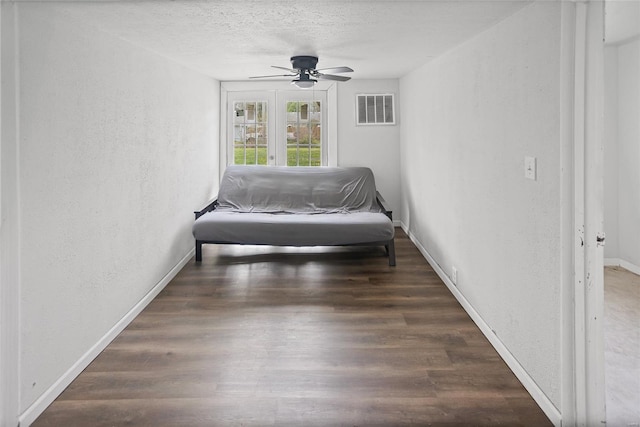 bedroom featuring baseboards, a textured wall, a textured ceiling, visible vents, and wood finished floors