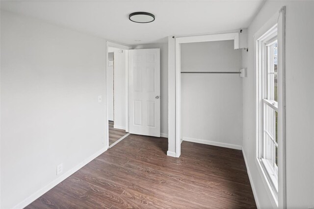 unfurnished bedroom with a closet, baseboards, and wood finished floors