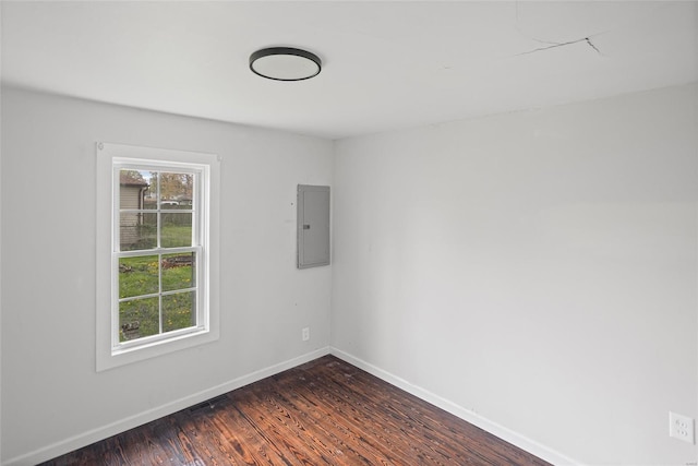 spare room with baseboards, dark wood finished floors, and electric panel