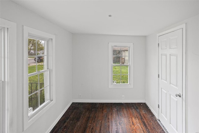 unfurnished room with dark wood-type flooring and baseboards
