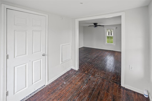 empty room featuring wood-type flooring, a ceiling fan, and baseboards