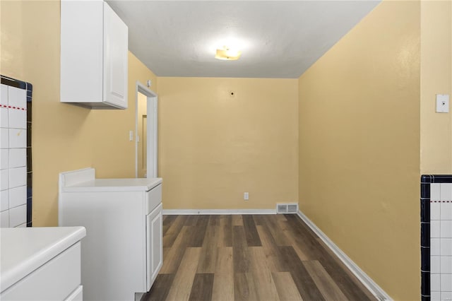 washroom with baseboards, visible vents, and dark wood-type flooring