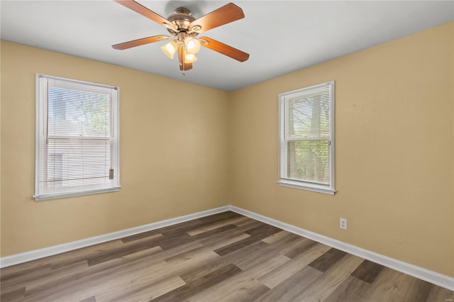 empty room featuring a ceiling fan, baseboards, plenty of natural light, and wood finished floors