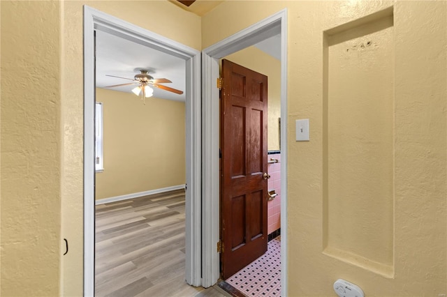 hallway featuring a textured wall and light wood finished floors