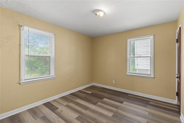 spare room with baseboards, dark wood-style floors, and a healthy amount of sunlight