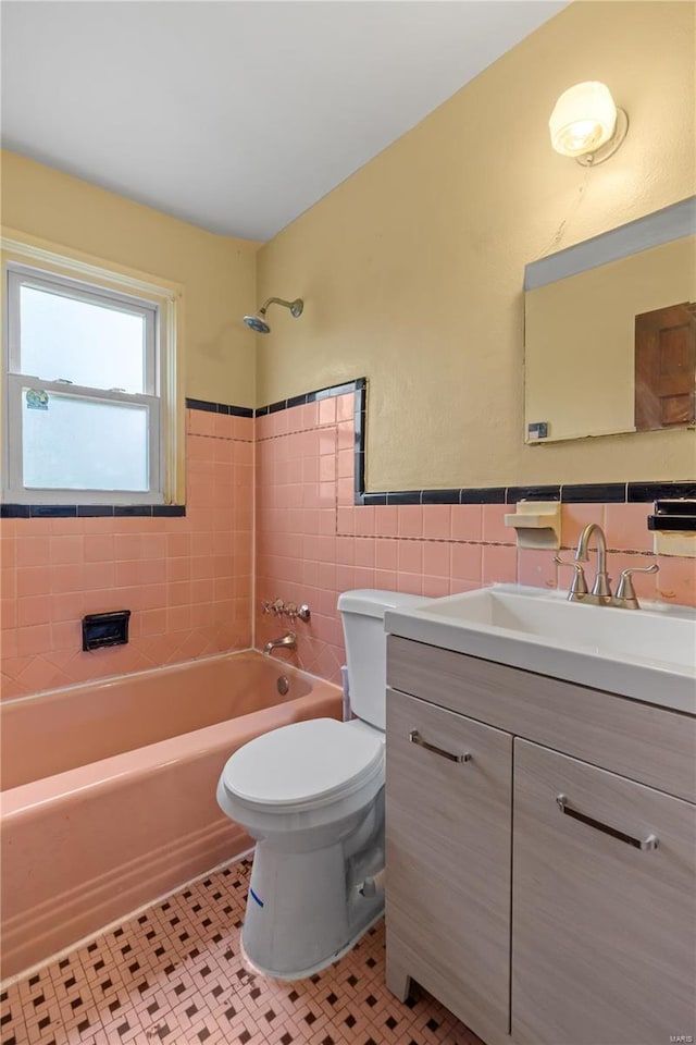 bathroom featuring vanity, shower / bathtub combination, toilet, tile patterned floors, and tile walls