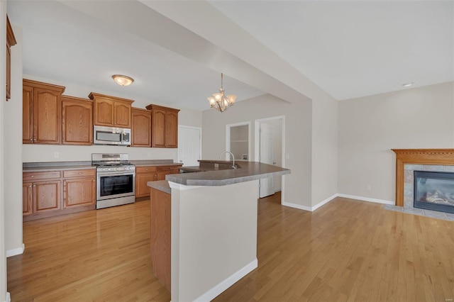 kitchen with brown cabinets, light wood-style floors, stainless steel appliances, baseboards, and an inviting chandelier