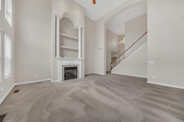 unfurnished living room with a high ceiling, visible vents, carpet floors, and baseboards