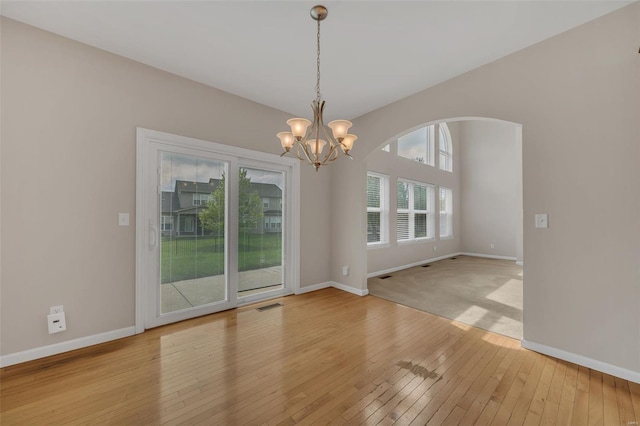 unfurnished dining area featuring an inviting chandelier, light wood-style flooring, and baseboards