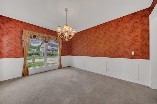 unfurnished room with a chandelier, wallpapered walls, a wainscoted wall, and carpet floors