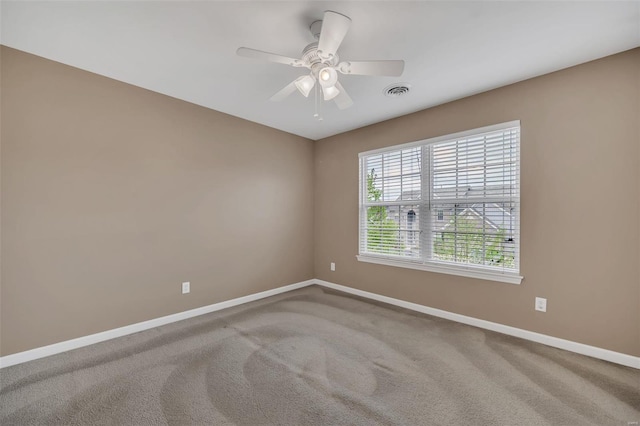 carpeted empty room with a ceiling fan, visible vents, and baseboards