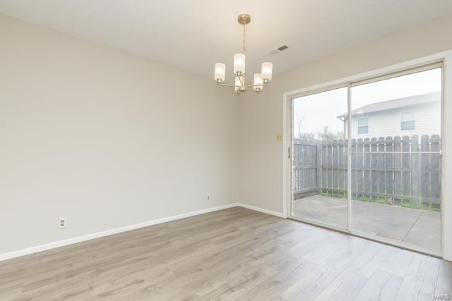 spare room with visible vents, baseboards, a chandelier, and light wood-style floors