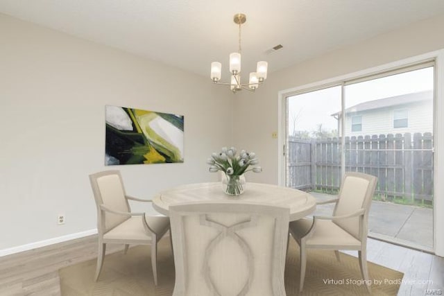 dining space featuring baseboards, a notable chandelier, wood finished floors, and visible vents