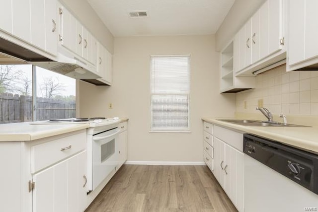 kitchen featuring a sink, tasteful backsplash, light wood-type flooring, visible vents, and white appliances
