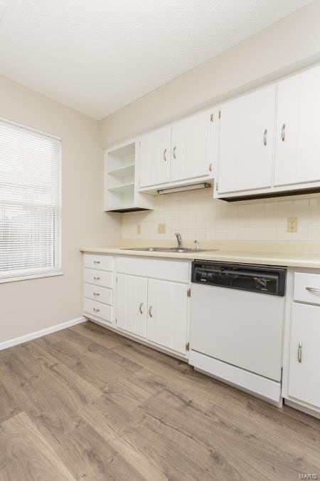 kitchen featuring dishwasher, white cabinetry, light wood-style flooring, and decorative backsplash