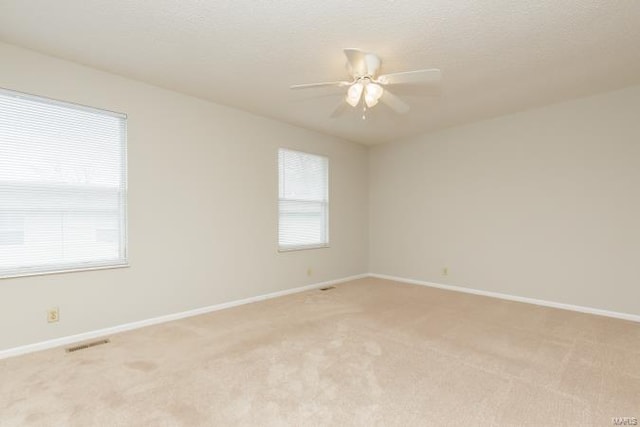 spare room with light colored carpet, baseboards, and visible vents