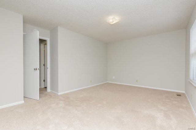 unfurnished room with light carpet, a textured ceiling, and baseboards