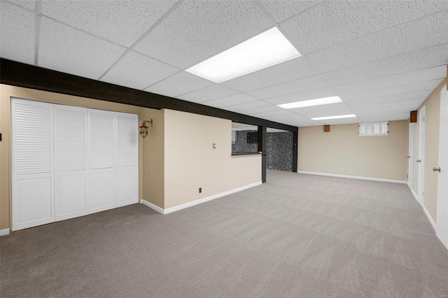 basement featuring carpet floors, baseboards, and a drop ceiling