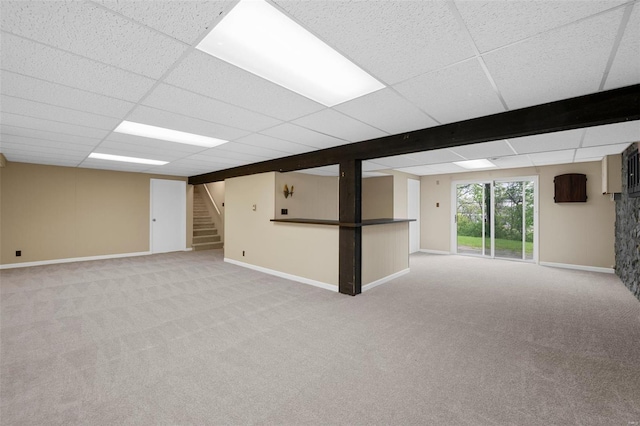 below grade area with stairway, carpet floors, baseboards, and a paneled ceiling