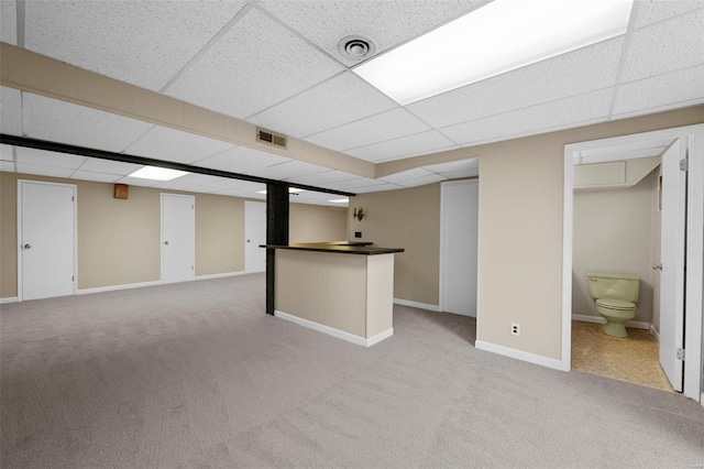 finished basement with baseboards, a drop ceiling, light colored carpet, and visible vents