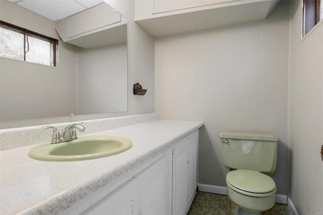half bathroom with vanity, baseboards, and toilet