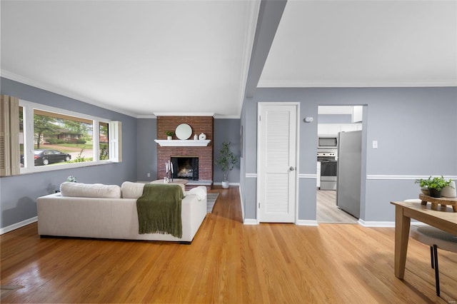 living room with ornamental molding, light wood finished floors, and a brick fireplace