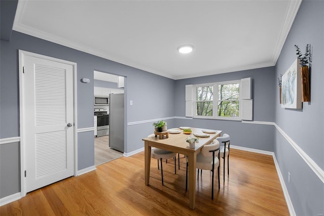 dining room featuring light wood-style floors, baseboards, and crown molding