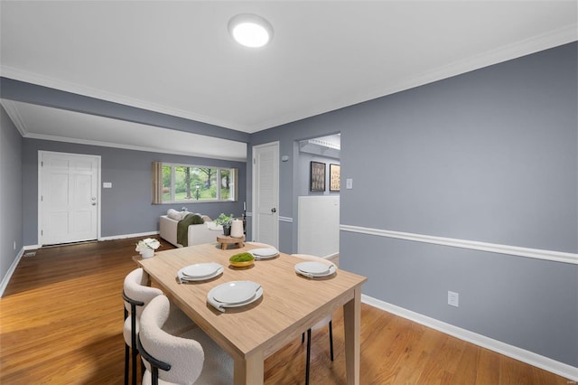 dining room with baseboards, crown molding, and wood finished floors