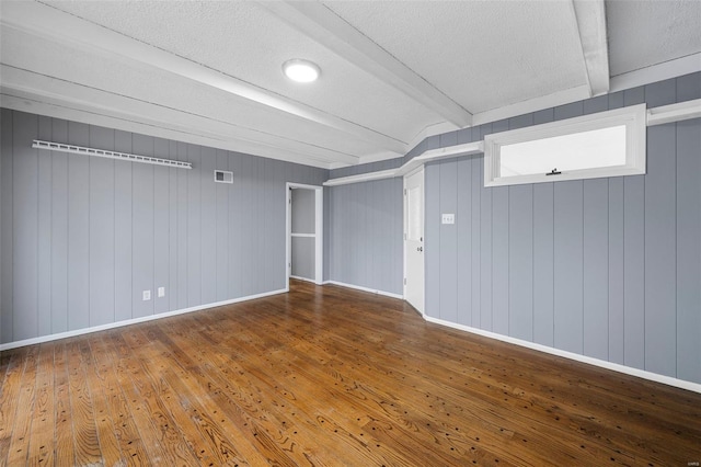 interior space featuring baseboards, a textured ceiling, hardwood / wood-style floors, and visible vents