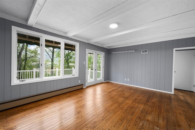 unfurnished room with beamed ceiling, a textured ceiling, baseboard heating, and hardwood / wood-style flooring