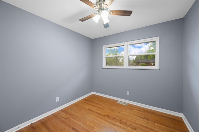 spare room with baseboards, ceiling fan, light wood-type flooring, and visible vents