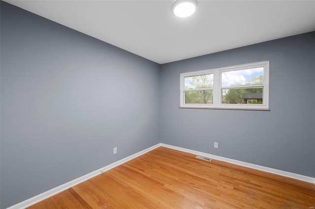 spare room with light wood-style floors, baseboards, and visible vents