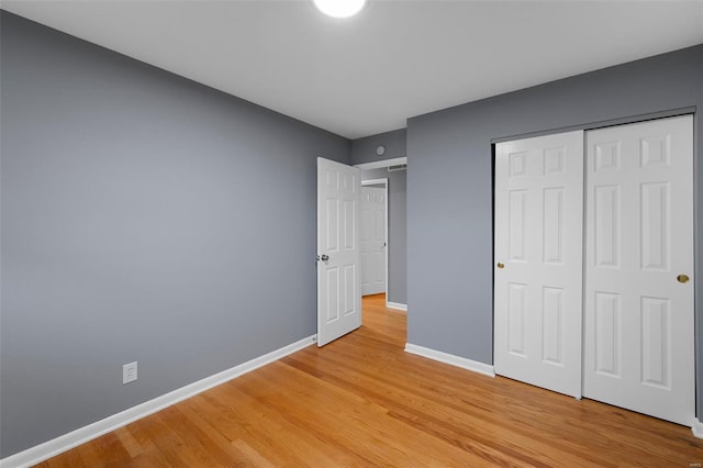 unfurnished bedroom featuring baseboards, a closet, and light wood finished floors