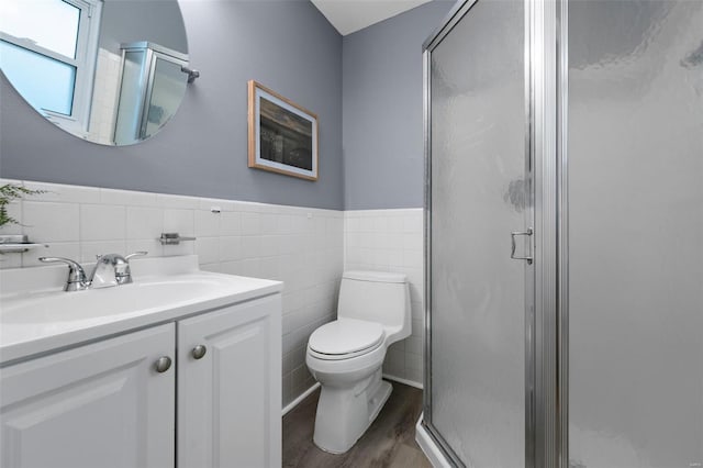 bathroom with vanity, toilet, tile walls, wood finished floors, and a stall shower