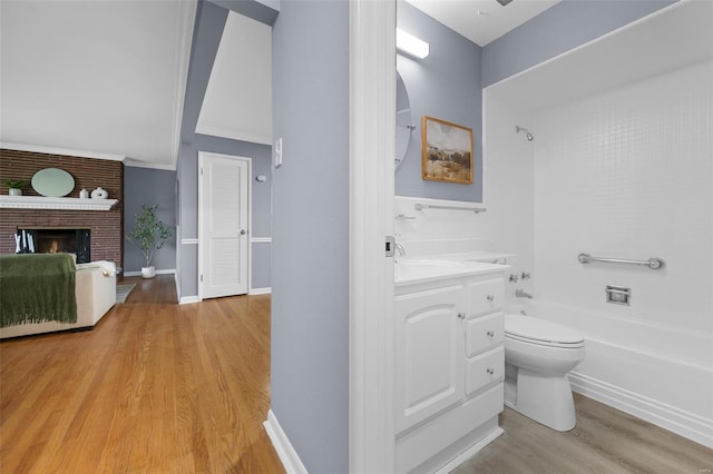 full bath with a fireplace, shower / tub combination, wood finished floors, vanity, and toilet