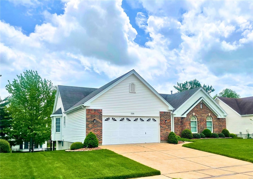 view of front of home featuring brick siding, driveway, a front lawn, and a garage