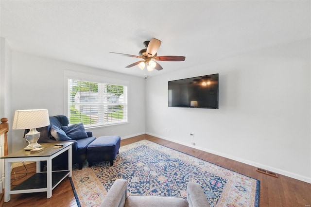 living room with baseboards, visible vents, ceiling fan, and wood finished floors