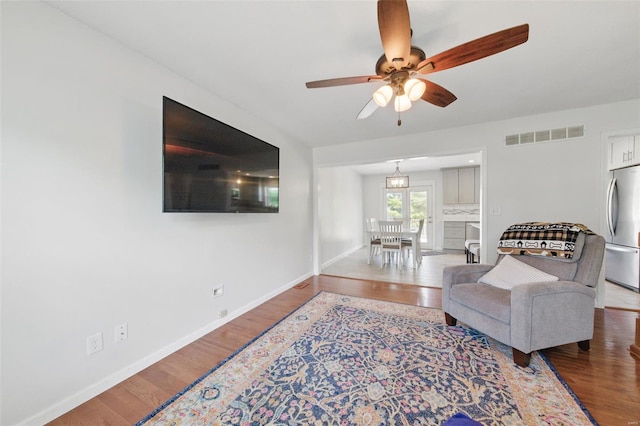living area with visible vents, a ceiling fan, and wood finished floors