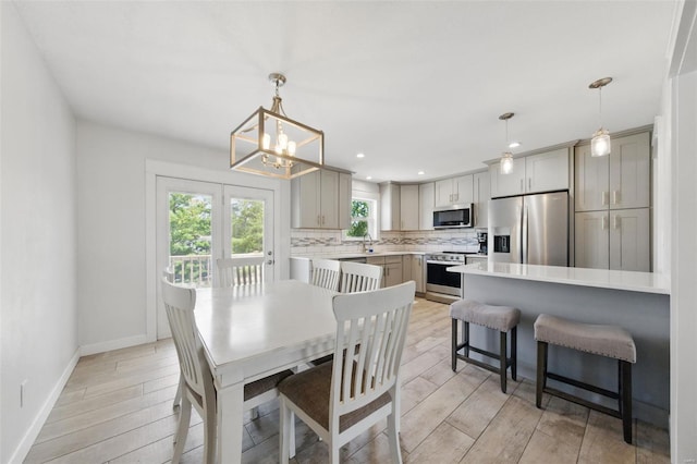 dining room with light wood-type flooring, recessed lighting, baseboards, and a notable chandelier