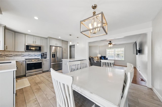 dining area with recessed lighting, ceiling fan with notable chandelier, and light wood-type flooring