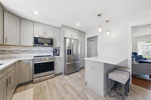 kitchen featuring gray cabinetry, appliances with stainless steel finishes, tasteful backsplash, and light wood-type flooring