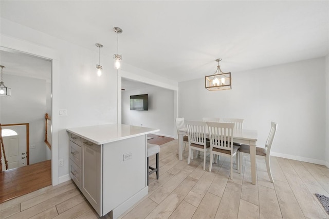kitchen featuring decorative light fixtures, light countertops, gray cabinetry, a notable chandelier, and light wood-style floors