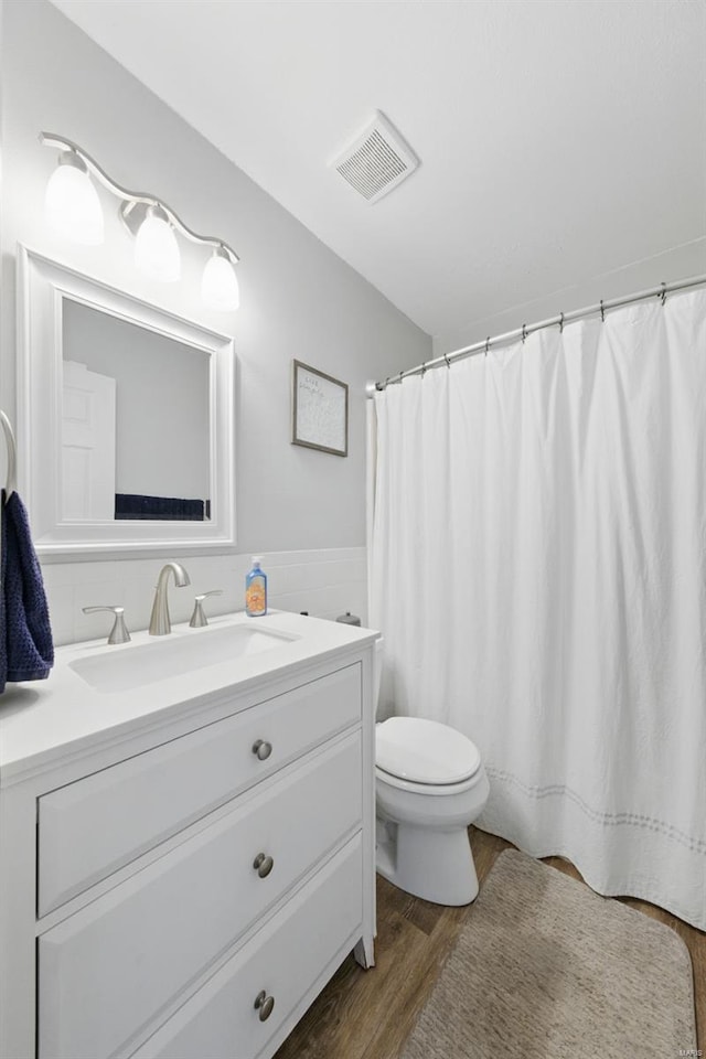 full bath with vanity, toilet, wood finished floors, and visible vents